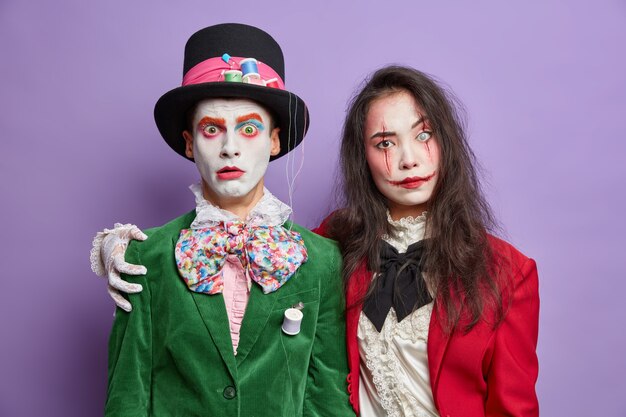 Dos amigos vestidos con disfraces de carnaval de halloween se abrazan y tienen relaciones amistosas usan maquillaje espeluznante celebran las fiestas aisladas en la pared púrpura
