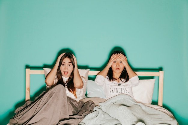 Dos amigos viendo la película emocionante en la cama