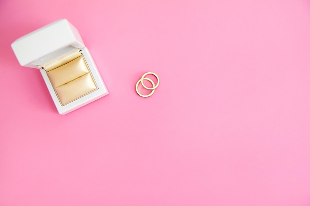 Foto gratuita dos anillos de oro cerca de la caja blanca sobre fondo de crema rosa