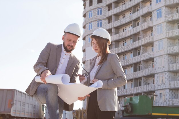 Dos arquitectos sostienen un plano y discuten un proyecto mientras trabajan juntos