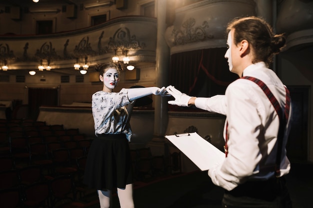 Dos artistas de mimo masculinos y femeninos ensayando en el escenario en el auditorio