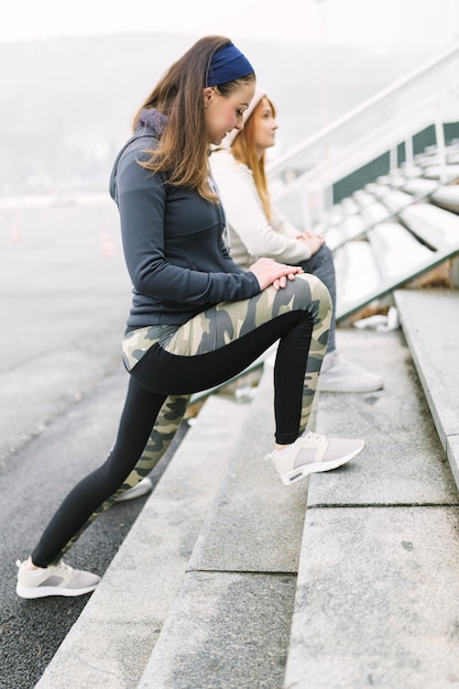 Foto gratuita dos atleta femenina estirando su pierna en pasos