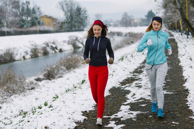 Dos atleta femenina trotar en la calle cerca del río en invierno