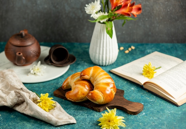 Dos bollos con forma de croissant colocados en una tabla de madera