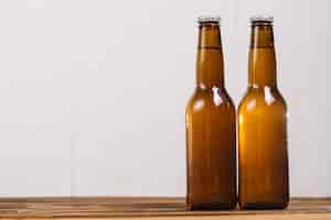 Foto gratuita dos botellas de cerveza cerradas en el escritorio de madera