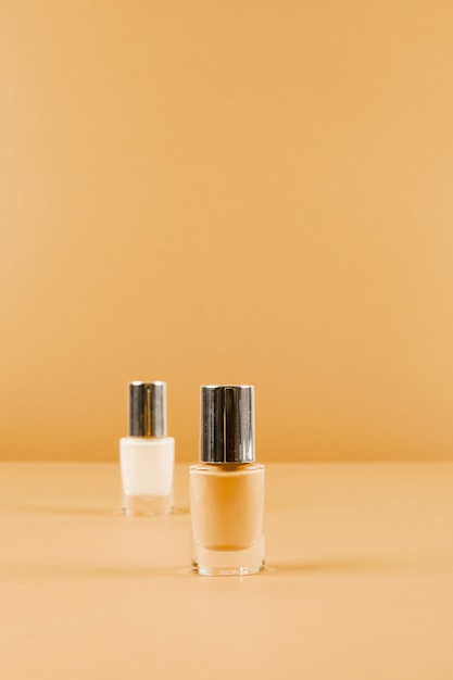 Dos botellas de esmalte de uñas en el fondo marrón abstracto
