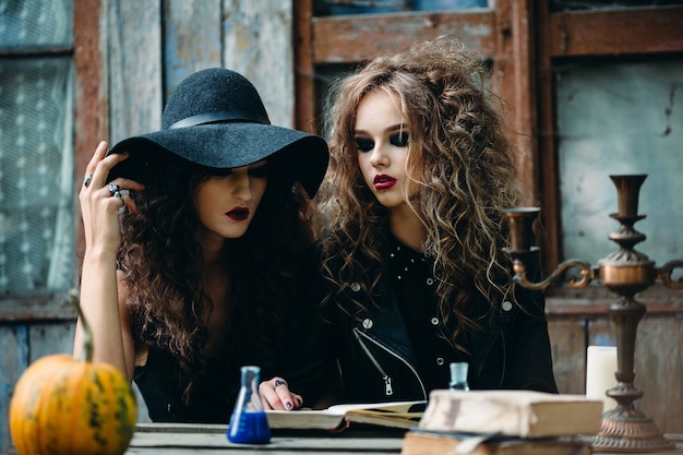 Dos brujas vintage sentados a la mesa en un lugar abandonado en vísperas de Halloween