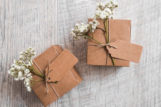 Dos cajas de cartón con etiqueta y flores de aliento de bebé sobre fondo de madera