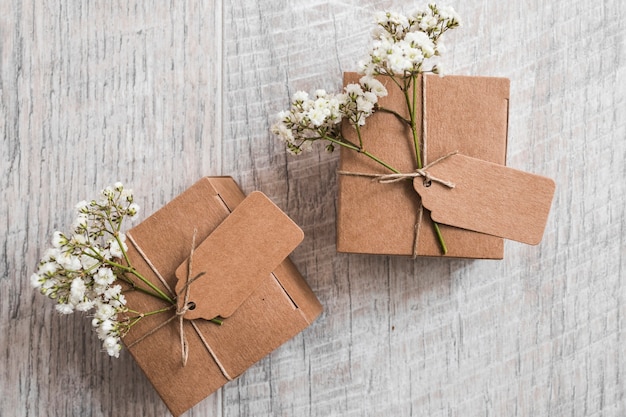 Dos cajas de cartón con etiqueta y flores de aliento de bebé sobre fondo de madera