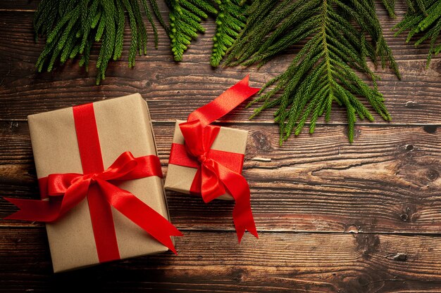 Dos cajas de regalo con lazo de cinta roja sobre fondo de madera