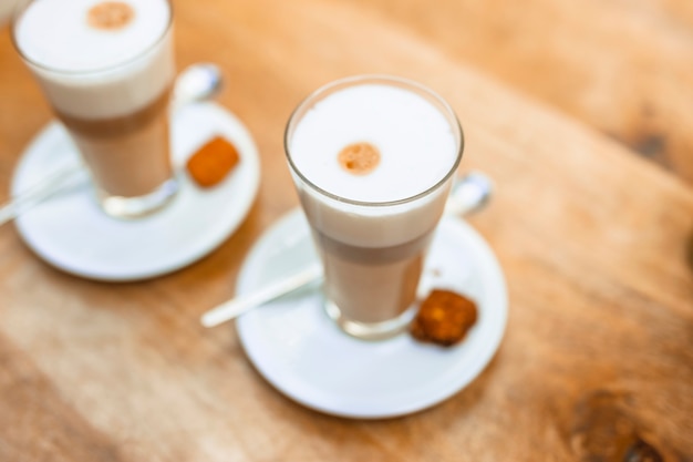 Dos capuchinos de café en un vaso transparente.