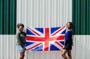 Foto gratuita dos chicas afroamericanas con la bandera de gran bretaña en las manos