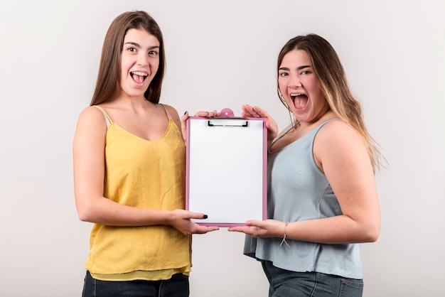 Dos chicas alegres presentando portapapeles