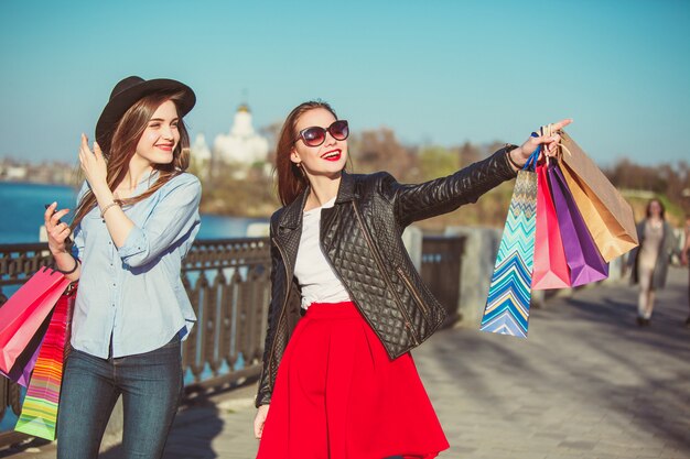 Dos chicas caminando con bolsas de compras en las calles de la ciudad en un día soleado