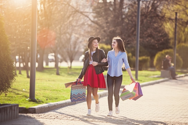 Dos chicas caminando con compras en las calles de la ciudad.