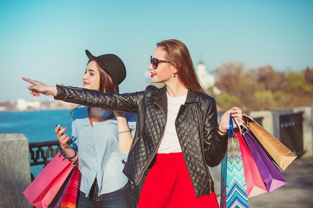 Dos chicas caminando con compras en las calles de la ciudad.