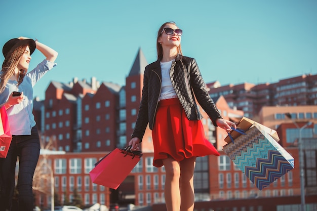 Dos chicas caminando con compras en las calles de la ciudad.