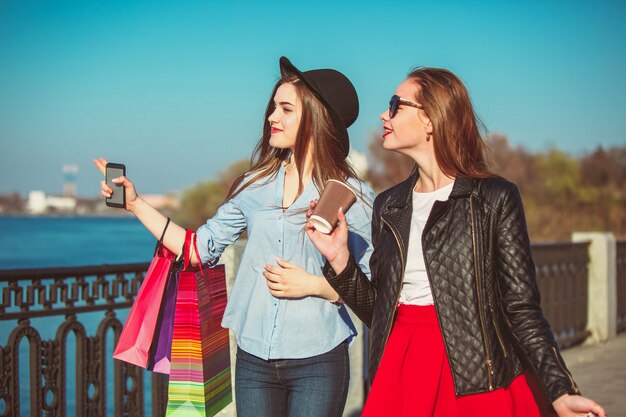 Dos chicas caminando con compras en las calles de la ciudad.