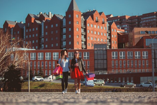 Dos chicas caminando con compras en las calles de la ciudad.