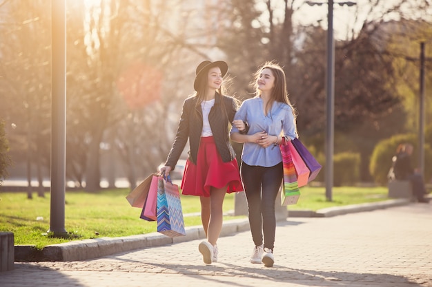 Dos chicas caminando con compras en calles de la ciudad