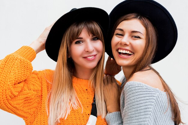 Dos chicas despreocupadas enviando beso de aire de pie en blanco