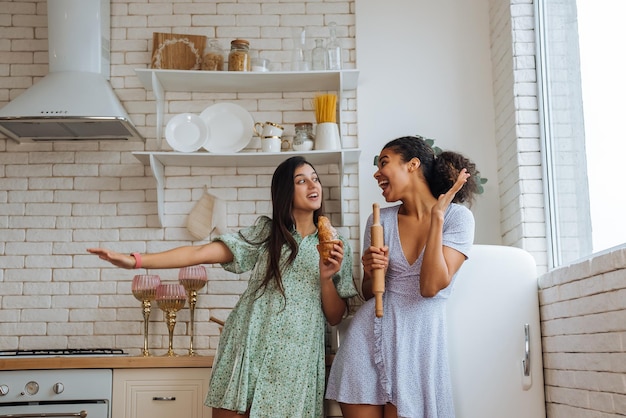 Dos chicas de diferentes razas divirtiéndose en la cocina