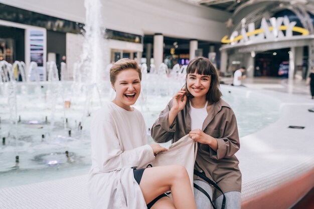 Foto gratuita dos chicas se divierten en el centro comercial, una fuente