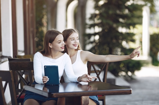 Dos chicas elegantes y con estilo en un café de verano.