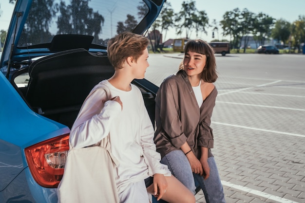 Dos chicas en el estacionamiento en el baúl abierto