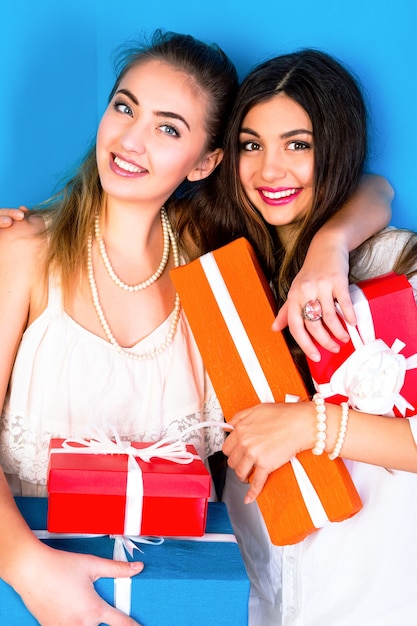 Dos chicas guapas amigas sosteniendo brillantes regalos navideños