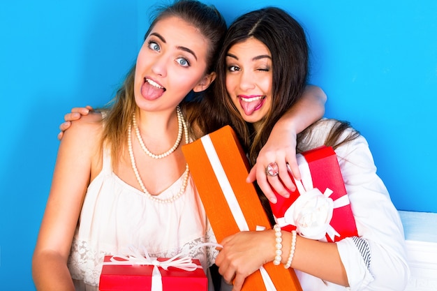 Dos chicas guapas amigas sosteniendo brillantes regalos navideños