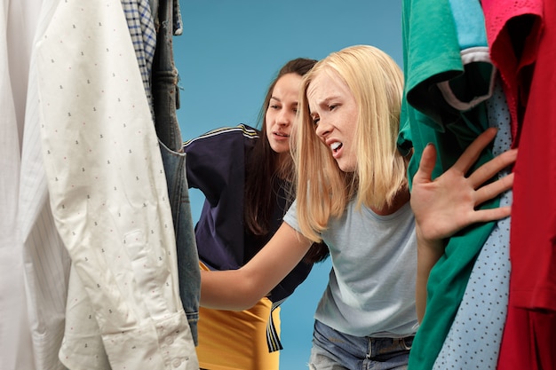 Las dos chicas guapas que miran vestidos y se lo prueban mientras eligen en la tienda