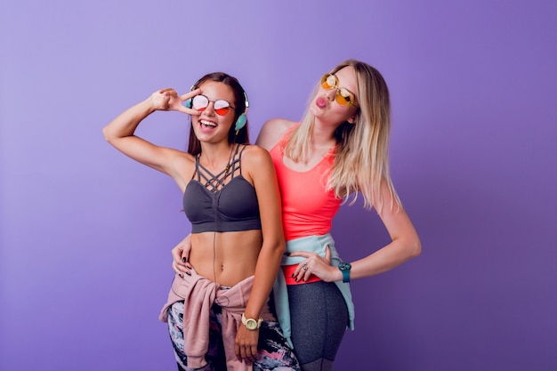 Dos chicas guapas en ropa deportiva de moda posando en púrpura