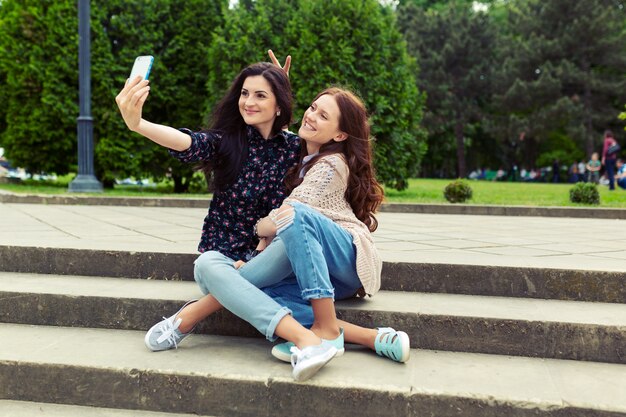 Dos chicas haciendo divertidas selfies en la calle, divirtiéndose juntas