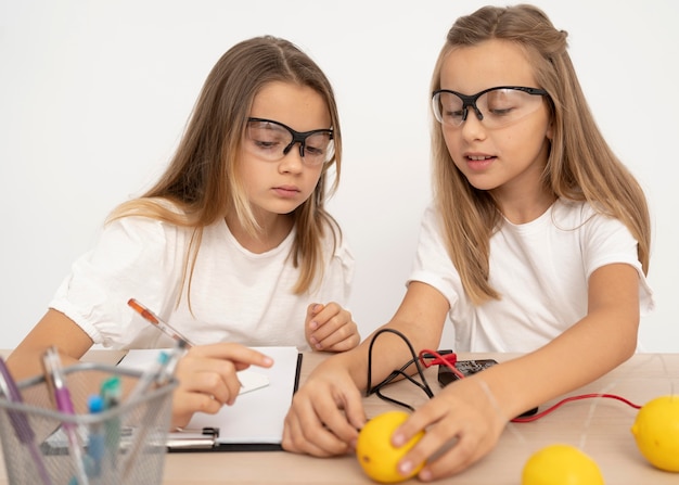 Dos chicas haciendo experimentos científicos con limones.