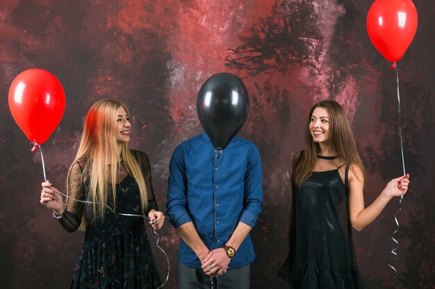 Dos chicas y un hombre con globos