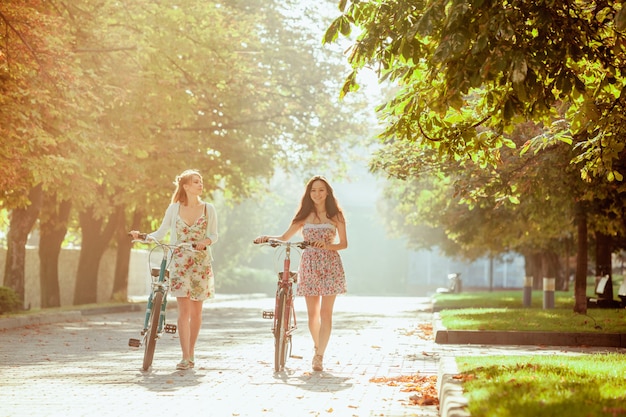 Las dos chicas jóvenes con bicicletas en el parque