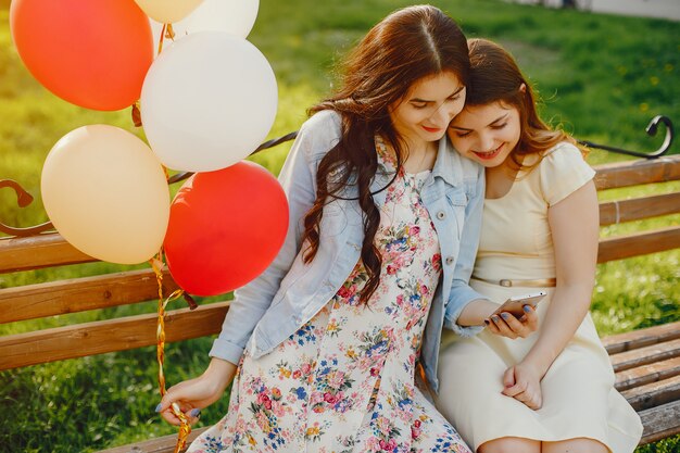 dos chicas jóvenes y brillantes pasan su tiempo en el parque de verano con globos