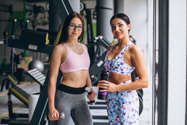 Dos chicas jóvenes entrenando en el gimnasio con equipo