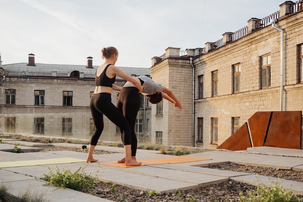 Dos chicas jóvenes practicando estiramientos y ejercicios de yoga hacen ejercicio juntas