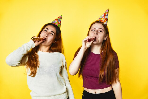 Dos chicas jóvenes con sombreros de cumpleaños están parados