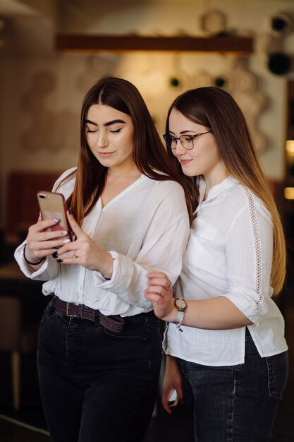 Dos chicas jóvenes con teléfonos inteligentes en el café