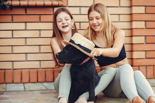 Dos chicas lindas en un parque de verano con un perro