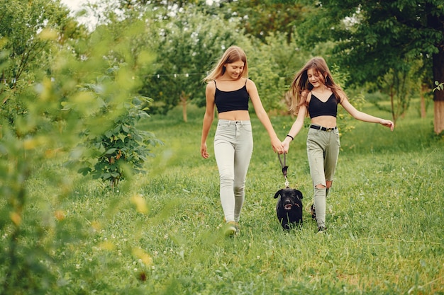 Dos chicas lindas en un parque de verano con un perro