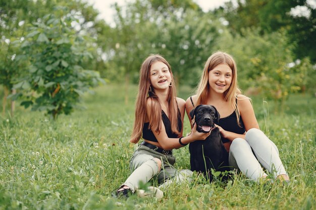 Dos chicas lindas en un parque de verano con un perro