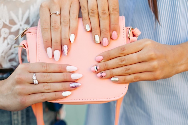 Dos chicas con manicura de diseño con bolso rosa de cuero.