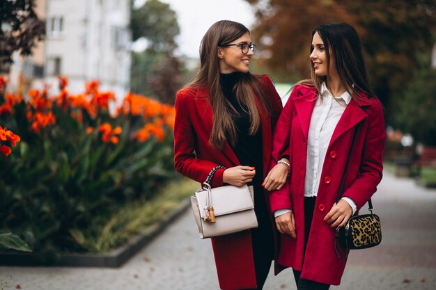 Dos chicas en modelos de abrigos rojos.