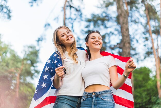 Dos chicas en la naturaleza con bandera americana