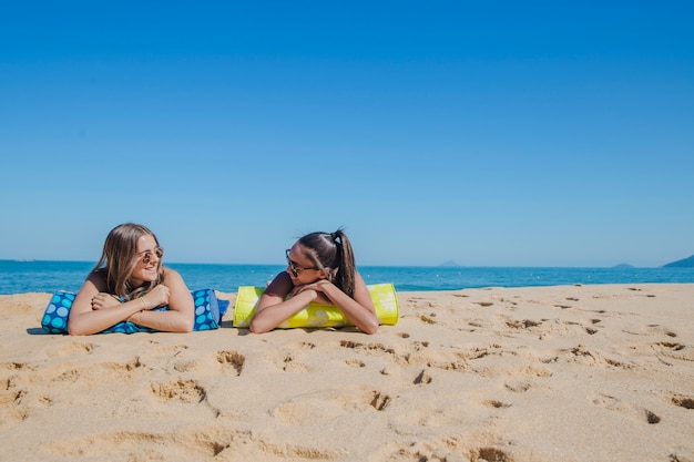 Dos chicas en la playa hablando