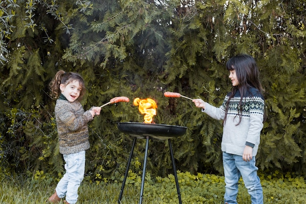 Dos chicas preparando salchichas en barbacoa